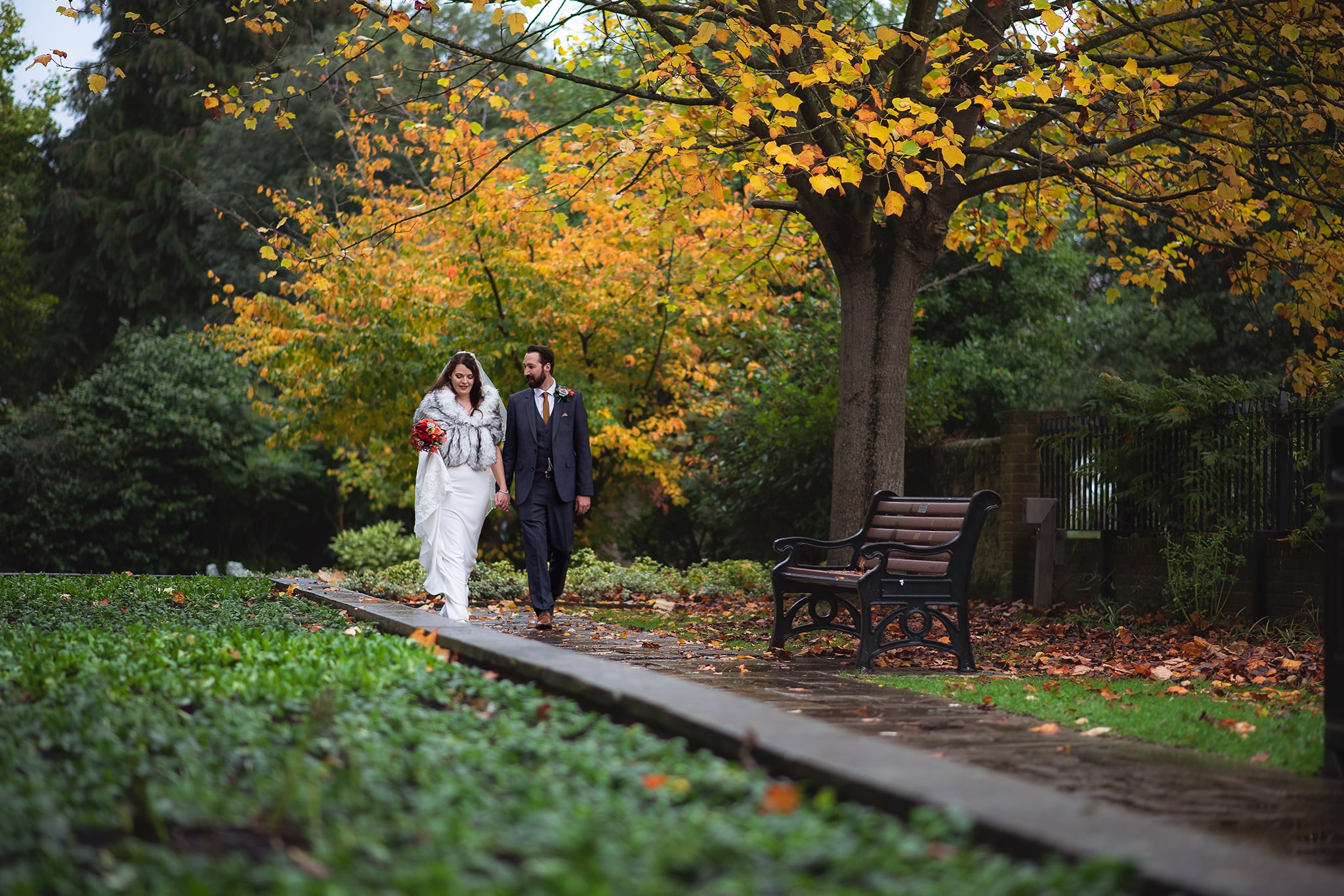 Wedding couple holding hands, walking in Autumn garden taken by Wedding Photgrapher Emma Seaney